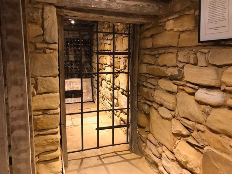 A barred gate to a stone cell in the cellar